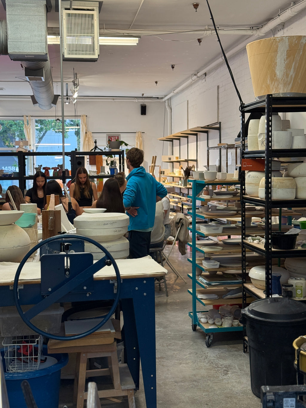 Workshop or studio with shelves of ceramic items and people working.